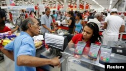 Un cliente coloca su dedo en un captahuellas para comprar productos en un supermercado estatal.