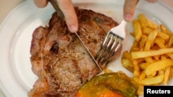 FILE - A beef steak is cut at the Taberna del Gijon restaurant in Madrid, Spain, July 26, 2017. 