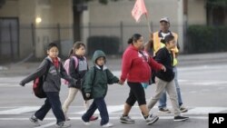 Anak-anak sekolah menyeberang jalan menuju sekolah mereka di SMP Sam Tasby, Vickery Meadow, Dallas (Foto: dok). Anak-anak yang dikarantina karena Ebola, sudah mulai diperbolehkan kembali masuk sekolah, termasuk Ikeoluwa Opayemi (7 tahun), siswa di Milford, Connecticut (31/10). 