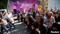 Protestors against police violence make their through the city pass an advertisement for a film featuring an image of Democratic Presidential Hillary Clinton near the Republican National Convention in Cleveland, Ohio, US, July 19, 2016. 