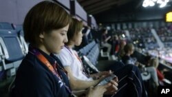 Atlet Jepang Miyuki Maeda dengan iPhone saat menonton pertandingan badminton pada Olimpiade London. (Foto: AP/Saurabh Das)