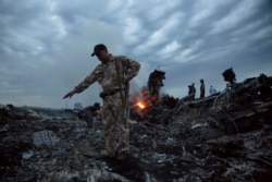 FILE - People walk amongst the debris at the crash site of a Malaysia Airlines flight MH17 near the village of Grabove, Ukraine, July 17, 2014.