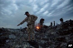 FILE - People walk amongst the debris at the crash site of a Malaysia Airlines flight MH17 near the village of Grabove, Ukraine, July 17, 2014.