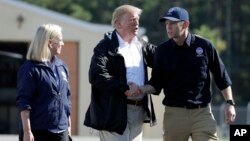 President Donald Trump shakes hands with FEMA Administrator Brock Long as Homeland Security Secretary Kirstjen Nielsen watches after visiting areas in North Carolina and South Carolina impacted by Hurricane Florence, Sept. 19, 2018, at Myrtle Beach International Airport in Myrtle Beach, S.C.