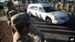 FILE - Utah National Guard members salute as a hearse containing the remains of Maj. Brent Taylor is escorted out of the National Guard base, Salt Lake City, Nov. 14, 2018. 