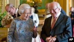President of Ireland Michael D Higgins laughs with Britain's Queen Elizabeth II as they view items of Irish interest extracted from the Royal Collection and displayed in the Green Drawing Room at Windsor Castle, in Windsor, England, April 8, 2014. 