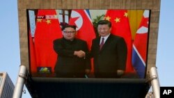 Sebuah layar televisi di Beijing memberitakan pertemuan antara Presiden China Xi Jingping dan pemimpin Korea Utara Kim Jong Un, Selasa (19/6). 