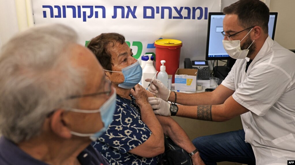 资料照片：一名以色列医疗工作者在耶路撒冷为一名老人接种新冠疫苗加强针。(2021年8月1日)(photo:VOA)