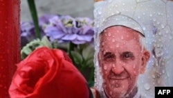 A candle depicting Pope Francis is placed at the statue of John Paul II outside the Gemelli hospital where Pope Francis is hospitalized in Rome on February 25, 2025.