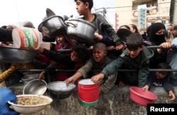 Palestinian children wait to receive food cooked by a charity kitchen amid shortages of food supplies in Rafah, Gaza Strip, on Feb. 13, 2024.