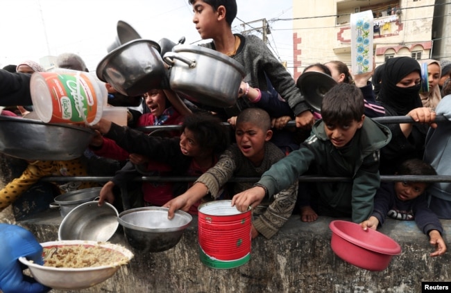 Palestinian children wait to receive food cooked by a charity kitchen amid shortages of food supplies in Rafah, Gaza Strip, on Feb. 13, 2024.