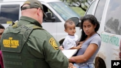 A mother migrating from Honduras holds her 1-year-old child as surrendering to U.S. Border Patrol agents after illegally crossing the border Monday, June 25, 2018, near McAllen, Texas. (AP Photo/David J. Phillip)