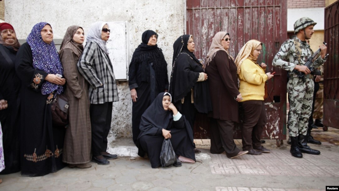 Mujeres hacen fila en El Cairo para votar en el referendo. Todos los centros de votación son custodiados por militares.