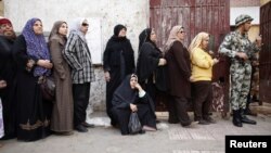 Mujeres hacen fila en El Cairo para votar en el referendo. Todos los centros de votación son custodiados por militares.