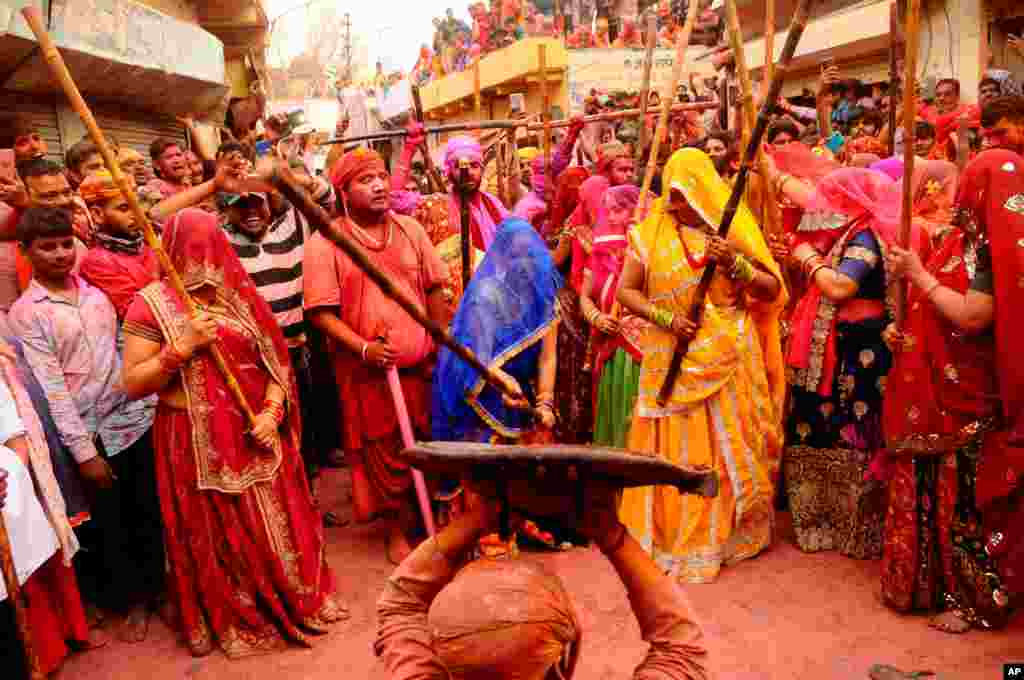 Indian women from the Barsana village beat a villager from Nandgoan with wooden sticks as he teases them during the Lathmar holi festival celebrations at the legendary hometown of Radha, consort of Hindu god Krishna, in Barsana.