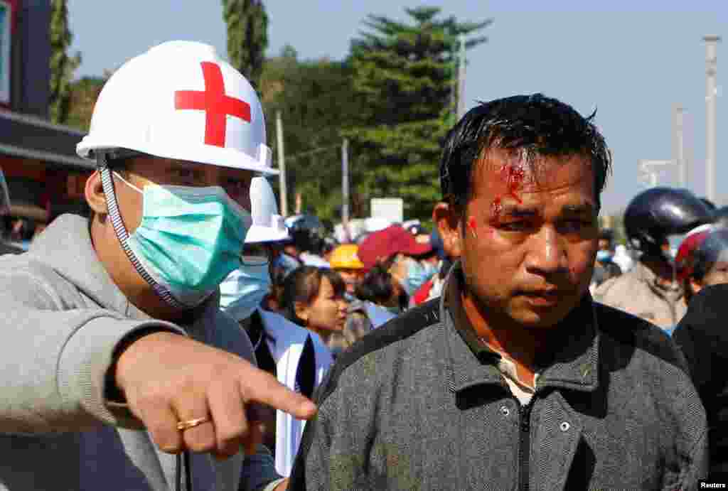 An injured protester is seen next to medical personnel, as protesters rally against the military coup and to demand the release of elected leader Aung San Suu Kyi in Naypyitaw, Myanmar, Feb. 9, 2021.