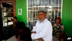 Muzitohtahon (tengah), seorang petani Uighur, berdiri di luar sebuah toko kelontong di Unity New Villaged di Hotan, barat wilayah Xinjiang, China, 21 September 20218. (Foto: Andy Wong/AP Photo)