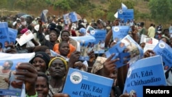 Parents, tuteurs et amis entonnent des chansons traditionnelles et portent des affiches pour la prévention du VIH/SIDA lors d'une cérémonie d'initiation masculine de l'adolescence à l’âge adulte dans le village de Njoloma, au Malawi, le 27 août 2006.