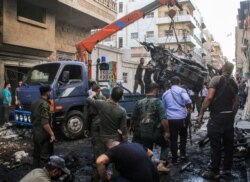 Syrian Kurdish security forces lift the wreckage of a rigged car which detonated outside the Syriac Orthodox Church of the Virgin Mary in Qamishli in northeast Syria, July 11, 2019.