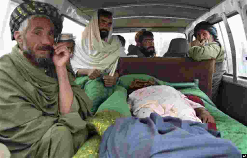 Afghan men sit in a bus with the body of a person who was allegedly killed by a U.S. service member in Panjwai, Kandahar province south of Kabul, Afghanistan, Sunday, March 11, 2012. Afghan President Hamid Karzai says a U.S. service member has killed more