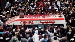 People throw rose petals on an ambulance carrying the body of Pakistani Sufi singer Amjad Sabri during his funeral in Karachi, Pakistan, June 23, 2016.