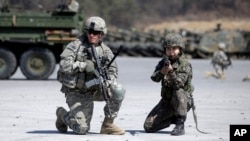 FILE - A U.S. Army soldier and a South Korean Army soldier take their position during joint military exercises between South Korea and the United States in Pocheon, north of Seoul, South Korea, March 25, 2015.