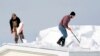 D.J. Schloss, left, and Doug Metz clear snow from a roof on Abbey Lane in Alden, N.Y., Nov. 20, 2014.