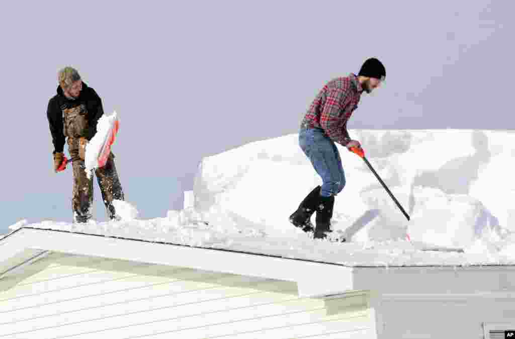 D.J. Schloss, left, and Doug Metz shovel off a roof on Abbey Lane in Alden, N.Y., Nov. 20, 2014.