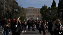 FILE - People walk in front of the Greek Parliament, in central Athens, Jan. 28, 2019. 