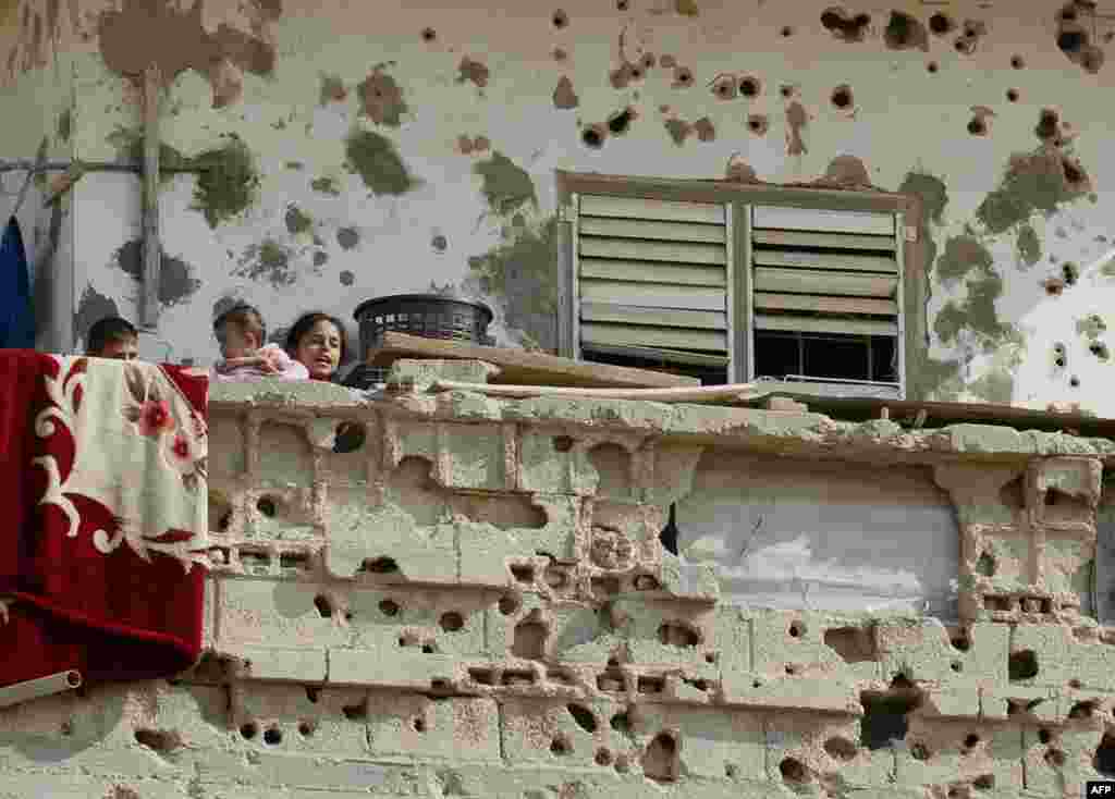 Palestinian children stand on the balcony of their family house which was damaged during an Israeli army operation launched after the killing of top Hamas military commander Ahmed Jaabari last year, in Rafah, southern Gaza Strip.