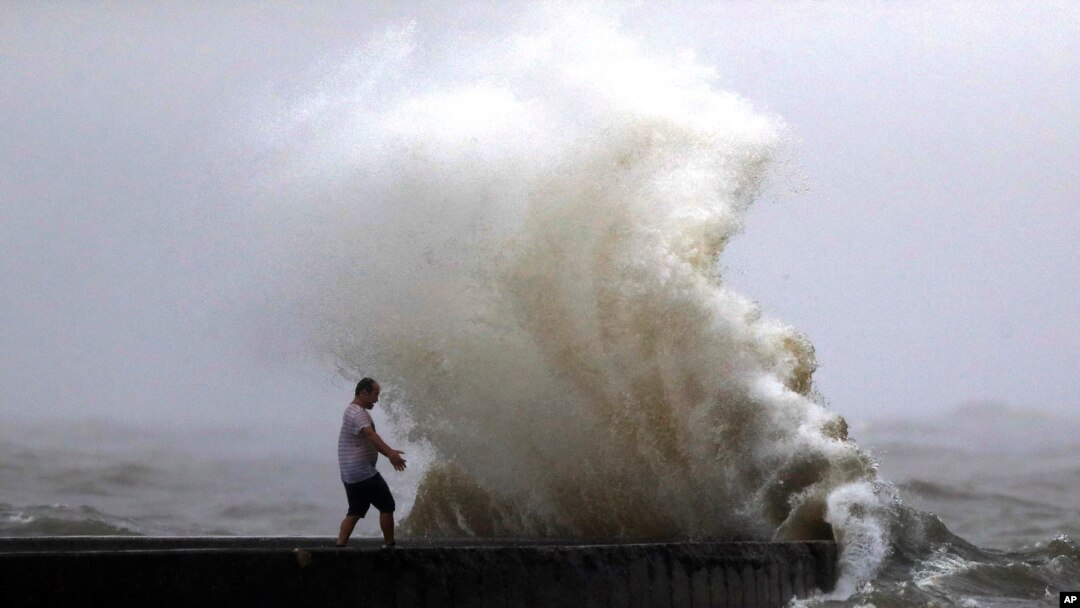 A wave crashes as a man stands on a jetty near Orleans Harbor in Lake Pontchartrain in New Orleans, June 7, 2020, as Tropical Storm Cristobal approaches the Louisiana Coast. 