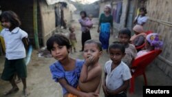 A Rohingya refugee girl carries a baby inside a refugee camp in Sitwe, in the state of Rakhine, Myanmar, March 4, 2017. 