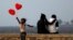 Seorang anak tampak kecewa setelah gagal menjual balon berbentuk hati kepada pasangan muda-mudi di belakangnya pada Hari Valentine di Mumbai, India.