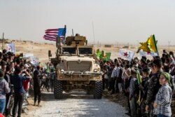 Syrian Kurds gather around a U.S. armored vehicle during a demonstration against Turkish threats on the outskirts of Ras al-Ain town in Syria's Hasakeh province near the Turkish border, Oct. 6, 2019.