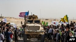 Syrian Kurds gather around a U.S. armored vehicle during a demonstration against Turkish threats on the outskirts of Ras al-Ain town in Syria's Hasakeh province near the Turkish border, Oct. 6, 2019.