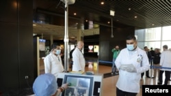 Anggota staf medis mengenakan alat pelindung diri bersiap memeriksa suhu para calon penumpang di Bandara Internasional Ratu Alia di Amman, Yordania, 4 Maret 2020. (Foto: Reuters)