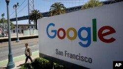 Seorang pria berjalan melewati papan iklan Google di San Francisco, 1 Mei 2019. 