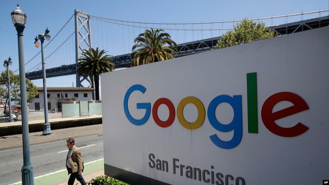 FILE - A man walks past a Google sign in San Francisco, May 1, 2019. 