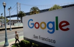 FILE - A man walks past a Google sign in San Francisco, May 1, 2019.