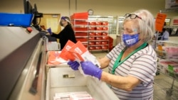 WASHINGTON – Election workers load ballots into a sorting machine at the King County elections office in Renton, Washington, on November 3, 2020.