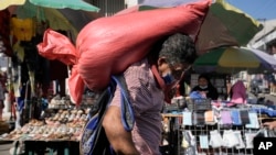 ARCHIVO - Un hombre carga un saco de maíz en el mercado de Comayaguela, en las afueras de Tegucigalpa, días después de las elecciones generales en Honduras, el 30 de noviembre de 2021. AP