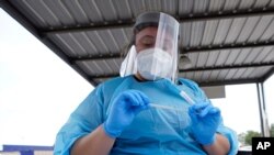 Shania Dod opens a test kit to collect a sample from a patient at a United Memorial Medical Center COVID-19 testing site, July 8, 2020, in Houston, Texas. 