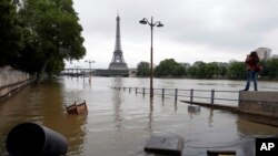 ARSIP – Seorang wanita mengambil foto di sisi sungai Seine yang terendam banjir di Paris (foto: AP Photo/Francois Mori)