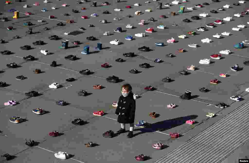 A child is surrounded by shoes, after Civil disobedience group Extinction Rebellion laid out 1,500 pairs of children's shoes in Trafalgar Square in central London to demand that government adopts a climate-friendly economic recovery plan. 