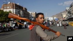 Un rebel hutí camina armado durante una protesta contra los bombardeos de la coalición regional liderada por Arabia Saudita en la capital de Yemen, Saná.