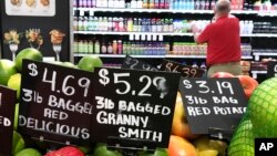 FILE - Price tags for delicious red, and granny smith apples and red potatoes are on display at a grocery store in Aventura, Fla., June14, 2018.