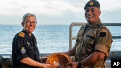 In this undated photograph  provided by the New Zealand Defense Force, Lieutenant Commander Tala Mafile'o of the Royal Tongan Navy presents Commander Yvonne Gray with a woody  vessel  arsenic  a memento of the RNZN's information   successful  the 50th Anniversary Fleet Review.