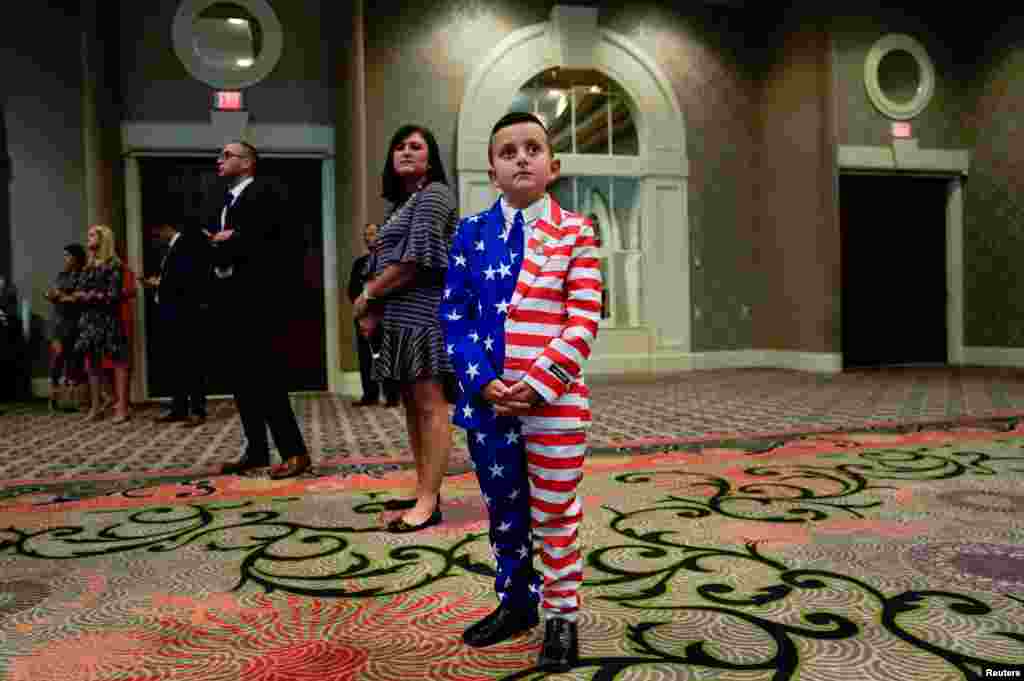 9-year-old Reed Elliotte in a U.S. flag outfit stands in the back of the room with his mother Larrietta listening to U.S. President Donald Trump address the AMVETS American Veterans convention in Louisville, Kentucky, Aug. 21, 2019.