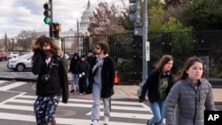 Abrigados contra el frío, los turistas caminan a través de una valla de seguridad que se ha instalado en el perímetro del complejo del Capitolio, el 2 de enero de 2025, en Washington. (Foto AP/Jacquelyn Martin).