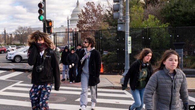 Abrigados contra el frío, los turistas caminan a través de una valla de seguridad que se ha instalado en el perímetro del complejo del Capitolio, el 2 de enero de 2025, en Washington. (Foto AP/Jacquelyn Martin).